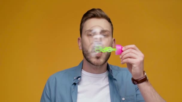 Schöner Mann Bläst Seifenblasen Lächelt Und Schaut Zeitlupe Die Kamera — Stockvideo