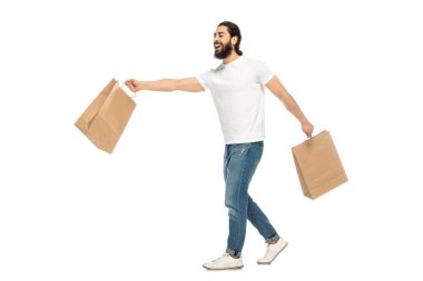 beyaz izole yürürken alışveriş torbaları tutan mutlu latin adam 