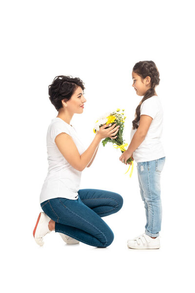 милый ребенок дарит цветы привлекательной латинской матери изолированы на белом
 