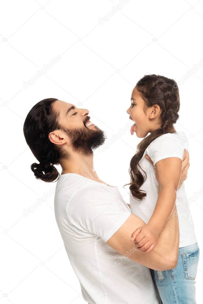 happy latin father smiling while holding in arms cute daughter showing tongue isolated on white 