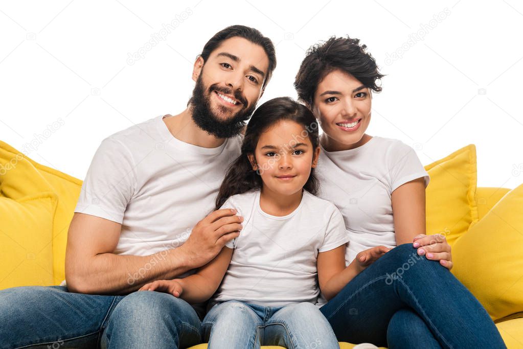 happy latin parents smiling while sitting on sofa with cute daughter isolated on white 