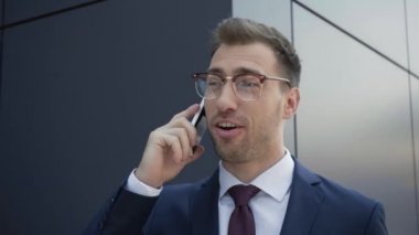 resmi giyim li işadamı akıllı telefonda konuşuyor, bina yakınında gülümsüyor ve gülüyor