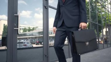 evrak çantası ile binanın yakınında yürüyen resmi giyimli işadamıkısmi görünümü
