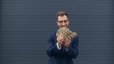 işadamı para sayıyor, gülümsüyor ve dolar banknotları atıyor 