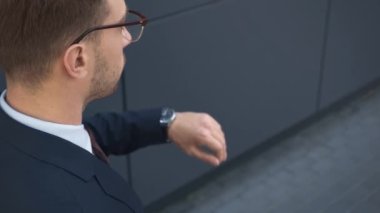 gözlüklü işadamının arka görünümü yandan saat bakarak