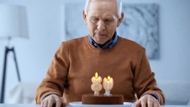Mumları ve dokunmadan gözleri ile Doğum günü pastası bakarak üzgün emekli adam seçici odak 