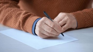 Kağıt üzerine yazarken üst düzey adam tutan kalem kırpılmış görünümü 