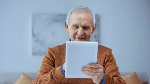 デジタルタブレットを使用して 自宅で笑顔を使用して幸せなシニア男性の選択的な焦点 — ストック動画