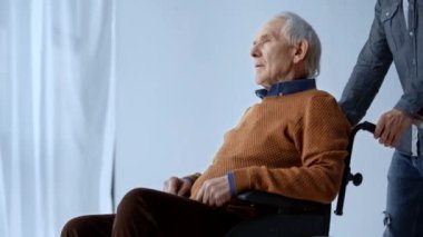Engelli kıdemli adam ile tekerlekli sandalye itmek adam kırpılmış görünümü 