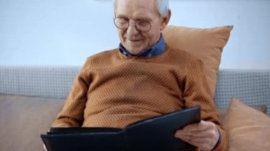 fotoğraf albümü bakarken gözlük gülümseyen neşeli kıdemli adam 