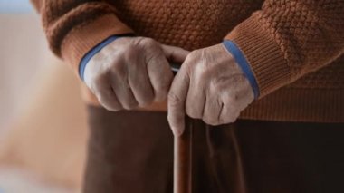 evde eller sallayarak ile yürüyen kamışı tutan hastalıklı kıdemli adamın kırpılmış görünümü 