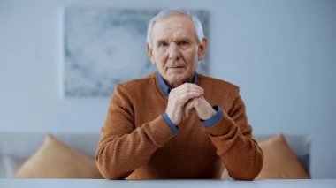 kızgın elleri ile oturan ve kamera bakarak sinirli kıdemli adam 