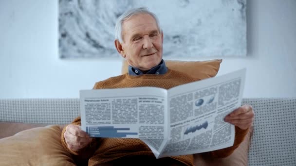 快乐的退休男子坐在轮椅上 在家里看书 — 图库视频影像