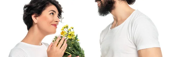 Panoramaaufnahme eines fröhlichen lateinamerikanischen Mannes, der einer attraktiven, auf Weiß isolierten Frau Blumen schenkt — Stockfoto