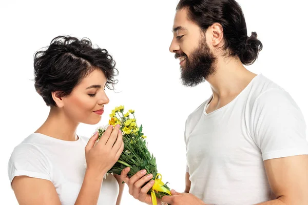 Brünett lateinisch Frau riecht Blumen in der Nähe schöner Mann isoliert auf weiß — Stockfoto