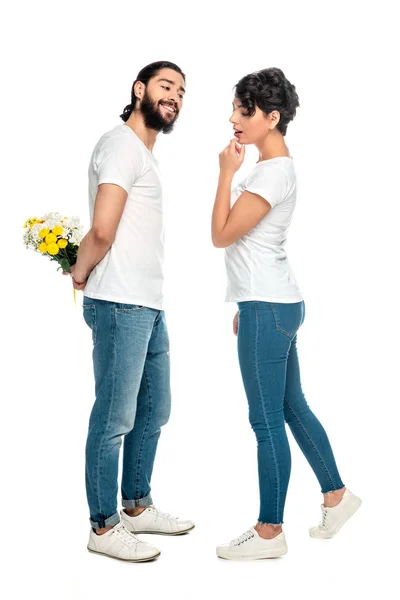 Привлекательная женщина, стоящая рядом с веселым латинским мужчиной с цветами, изолированными на белом — стоковое фото