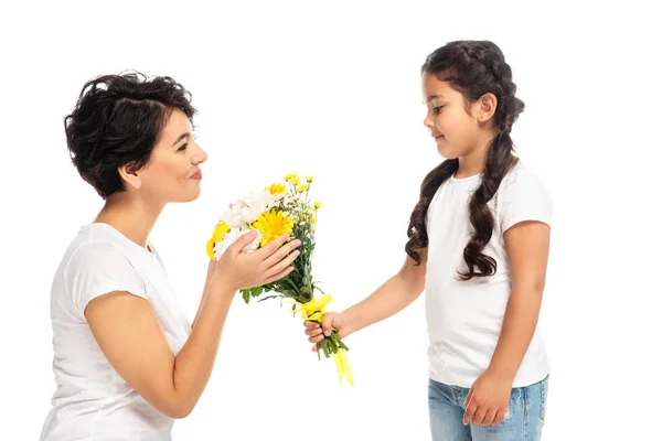 Happy kid giving flowers to attractive latin mother isolated on white — Stock Photo