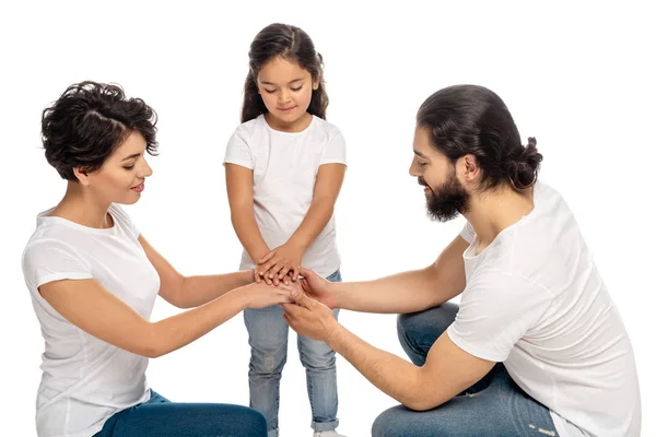 Feliz latina padres poniendo manos juntas con linda hija aislado en blanco - foto de stock