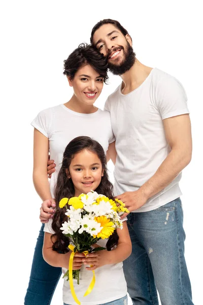 Latin parents smiling near cute daughter holding flowers isolated on white — Stock Photo