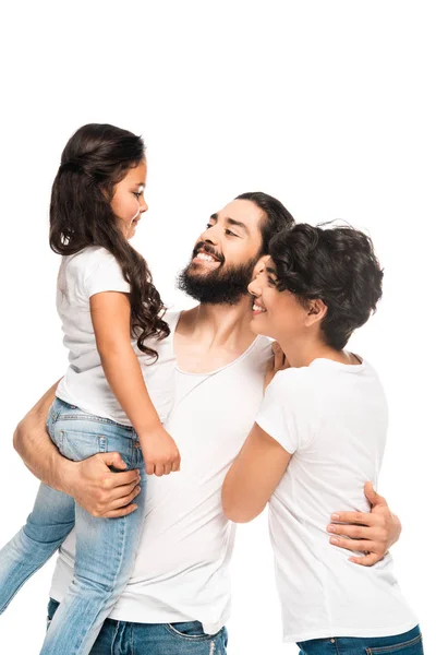 Barbudo latino sosteniendo en brazos adorable hija mientras sonríe cerca de esposa aislado en blanco - foto de stock