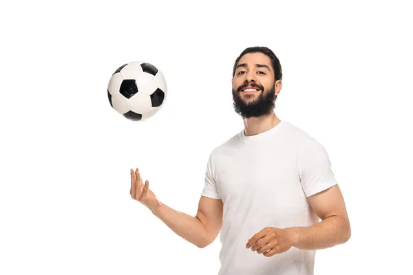Feliz latino lanzando en el aire pelota de fútbol y sonriendo aislado en blanco - foto de stock