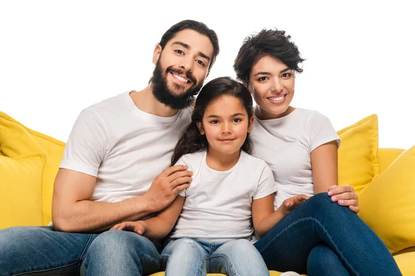 Feliz latina padres sonriendo mientras sentado en sofá con linda hija aislado en blanco - foto de stock