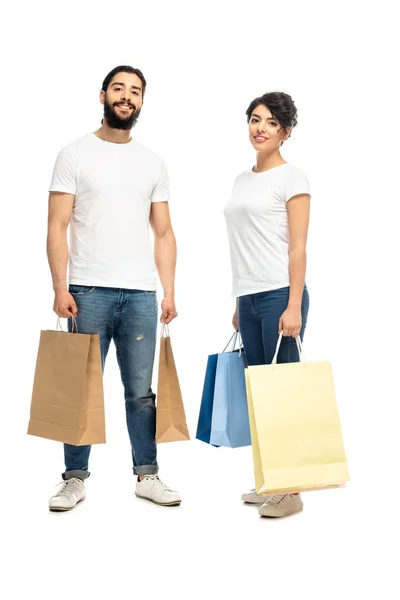 Felice latino uomo e donna in possesso di borse della spesa mentre in piedi isolato su bianco — Foto stock