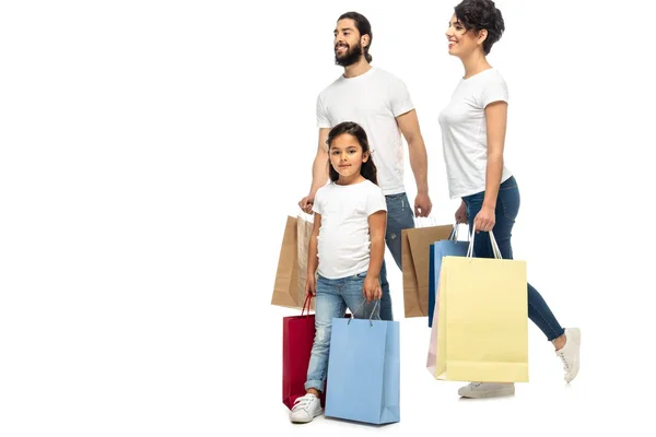 Padres latinos felices sosteniendo bolsas de compras mientras están de pie con el niño aislado en blanco - foto de stock