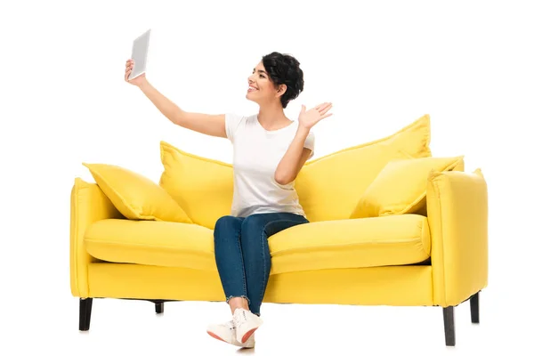 Cheerful latin woman holding digital tablet and waving hand while having video call isolated on white — Stock Photo