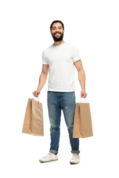 Homem latino feliz segurando sacos de compras e sorrindo isolado no branco — Fotografia de Stock
