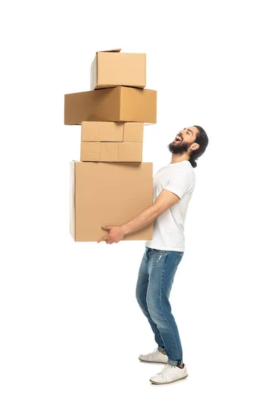 Hombre latino barbudo feliz sosteniendo cajas de cartón y sonriendo aislado en blanco - foto de stock