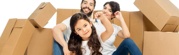 Plan panoramique de heureux latin enfant tenant des clés près des parents et des boîtes isolées sur blanc — Photo de stock