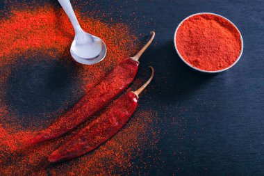 Red Chili pepper flakes and chili powder burst on black background