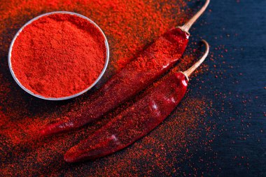 Red Chili pepper flakes and chili powder burst on black background