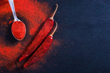 Red Chili pepper flakes and chili powder burst on black background