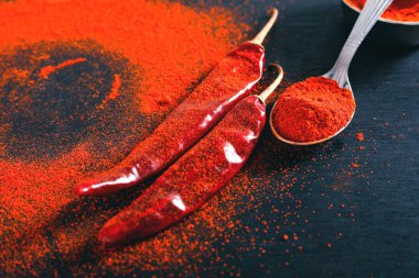 Red Chili pepper flakes and chili powder burst on black background