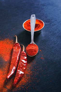 Red Chili pepper flakes and chili powder burst on black background