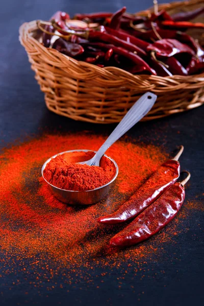 Red Chili pepper flakes and chili powder burst on black background