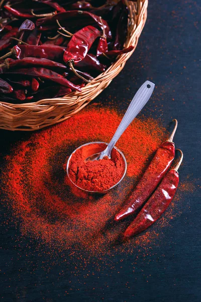 Red Chili pepper flakes and chili powder burst on black background