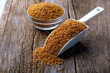 Cam kasede çemen otu tohumları ve ahşap arka planda kepçe