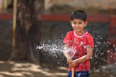 indian child playing with water tube