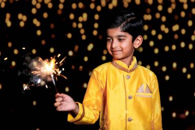 Cute Indian child celebrating Diwali festival with cracker and sparkle