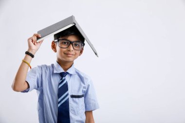 cute little Indian / Asian school boy wearing spectacles with book on head