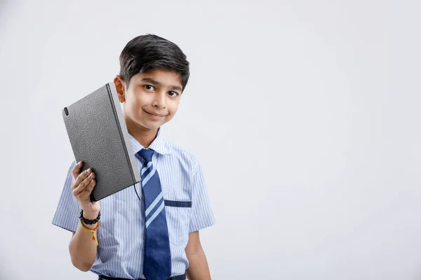 Cute little Indian/Asian school boy with note book isolated over white background