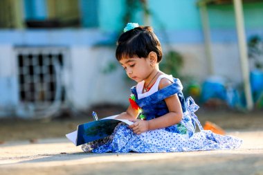 Indian Little Girl child writing on note book , studying 