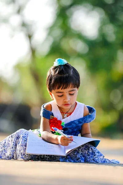Indian Little Girl child writing on note book , studying