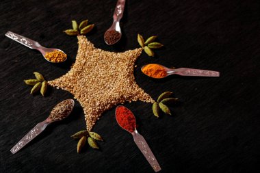 Siyah arka plan üzerine kaşık içinde baharatlar