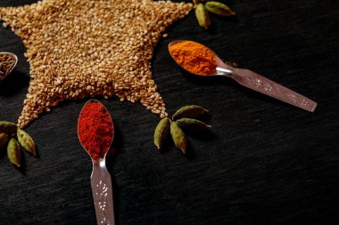 Siyah arka plan üzerine kaşık içinde baharatlar