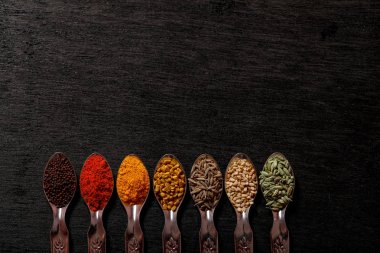 Siyah arka plan üzerine kaşık içinde baharatlar