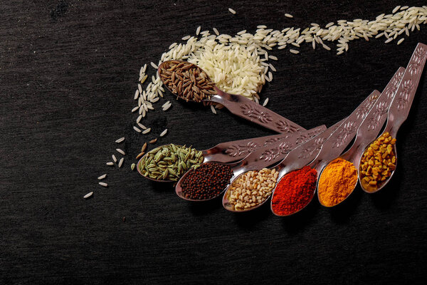 spices in spoons on black background